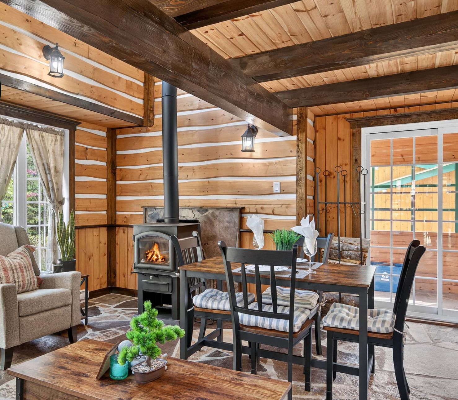 Acogedor interior de cabaña de madera con chimenea, una mesa de comedor y asientos cómodos.