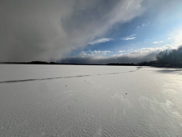 Un campo llano y extenso cubierto de nieve, con una línea de árboles distante y un cielo nublado.