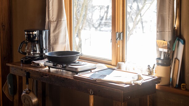 Una encimera de cocina con cafetera, sartén y una tableta.