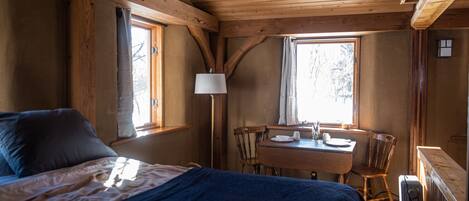 Una habitación de cabaña de madera con una cama, una mesa, sillas y una ventana.
