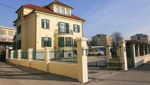 A two-story building with a balcony, a gated entrance, and a parked car in the background. - Budget room Hotel Vila Katrca (Ljubljana)