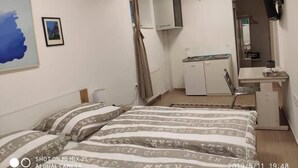 A bedroom with a bed, a small desk, a mirror, and a wardrobe. - Budget room Hotel Vila Katrca (Ljubljana)