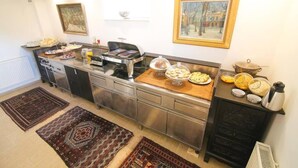 A modern kitchen with a buffet setup, including a stove, various food items, and a coffee maker. - Budget room Hotel Vila Katrca (Ljubljana)
