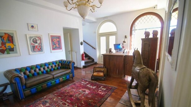 A living room with a patterned sofa, a wooden statue, and a red rug. - Budget room Hotel Vila Katrca (Ljubljana)