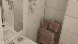 A bathroom with a shower, a sink, and a towel rack. - Budget room Hotel Vila Katrca (Ljubljana)