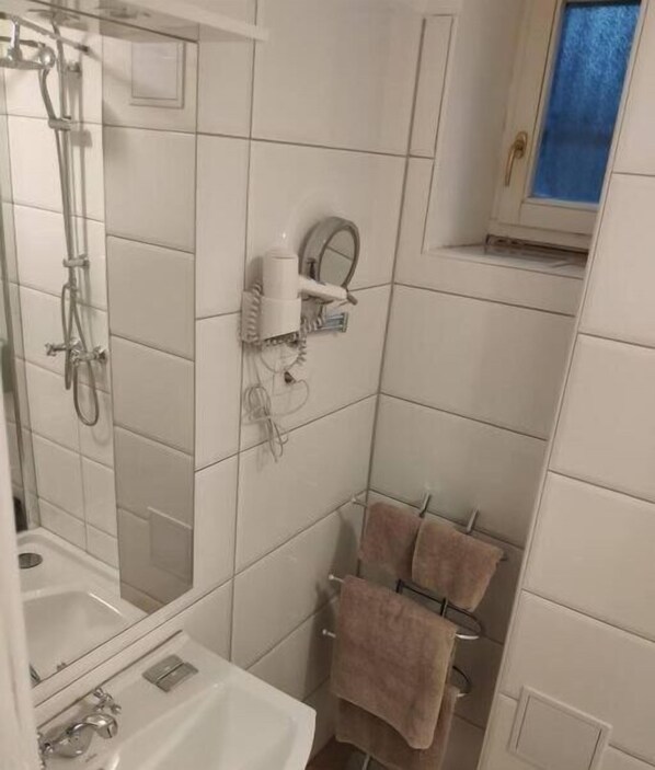 Ein Badezimmer mit Dusche, Waschbecken und Handtuchhalter.