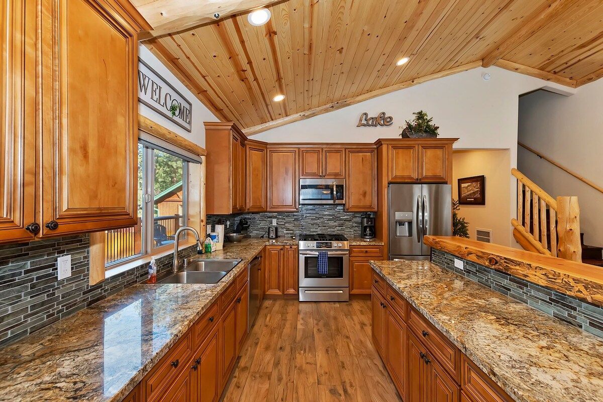 A modern kitchen with wooden cabinets, granite countertops, and a stone backsplash.