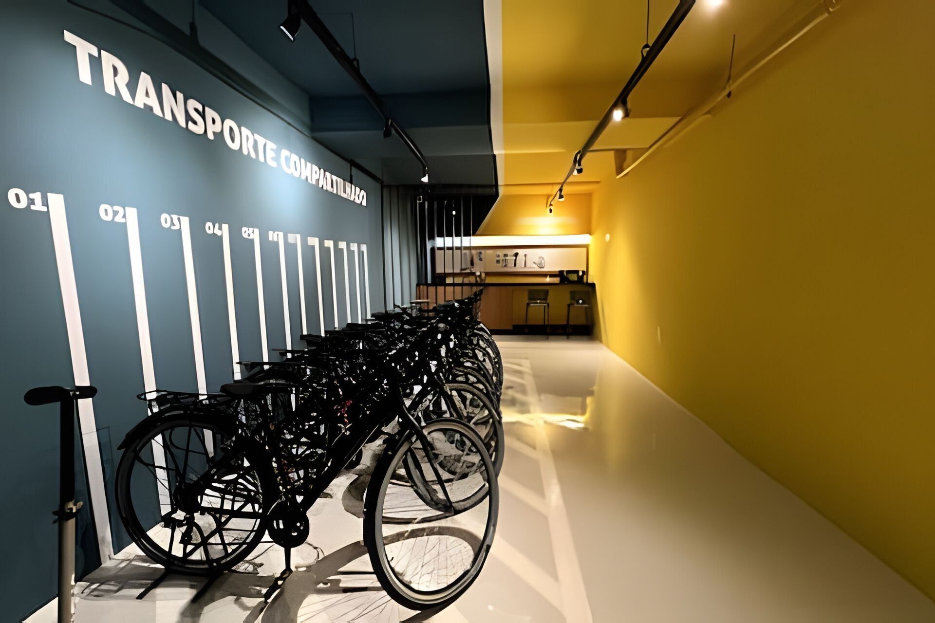 Varias bicicletas estacionadas contra una pared con un letrero que dice "TRANSPORTE COMPATILHABA".