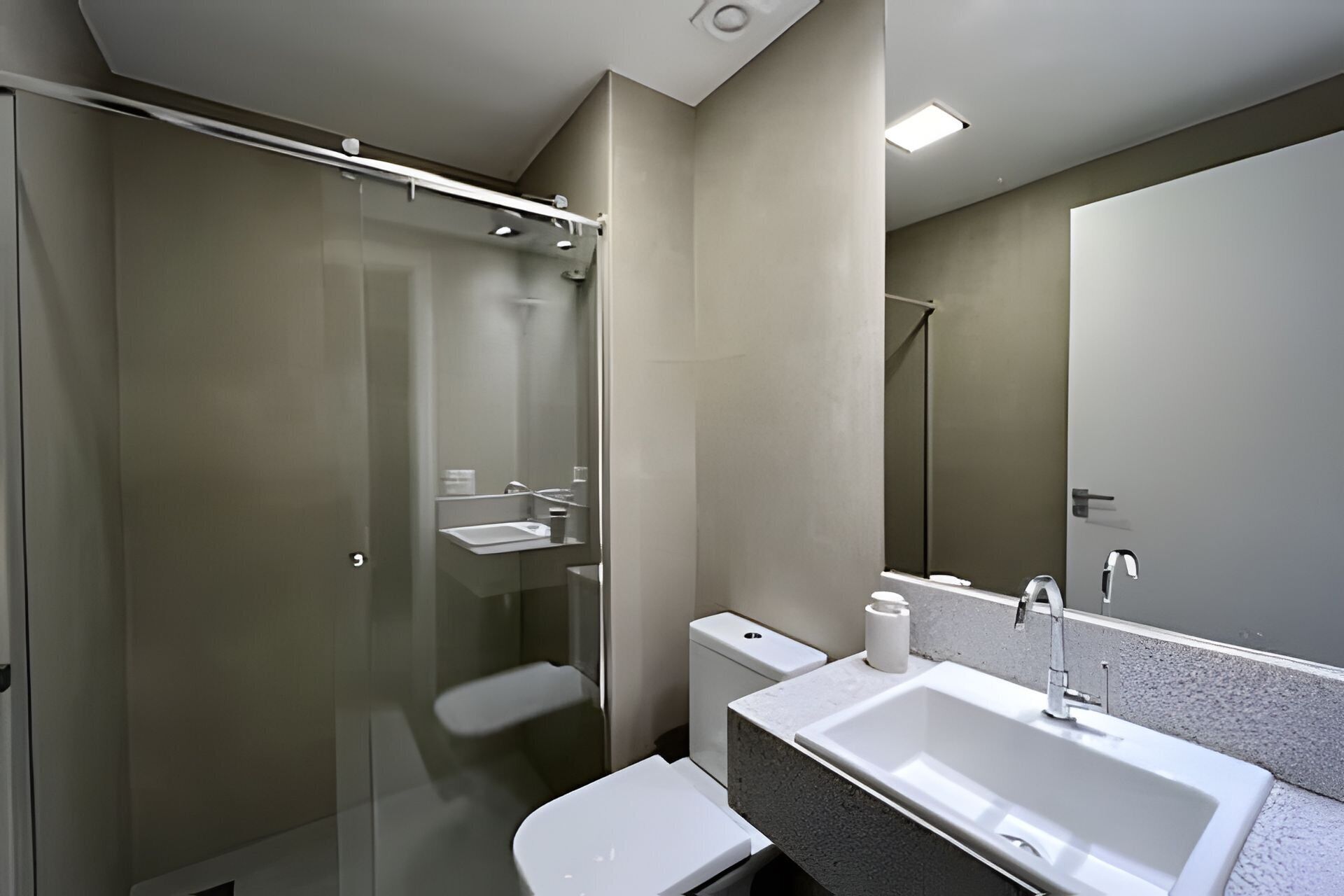 A modern bathroom with a glass-enclosed shower, a white sink, and a toilet.