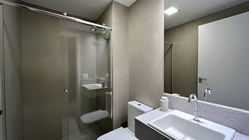 A modern bathroom with a glass-enclosed shower, a white sink, and a toilet.