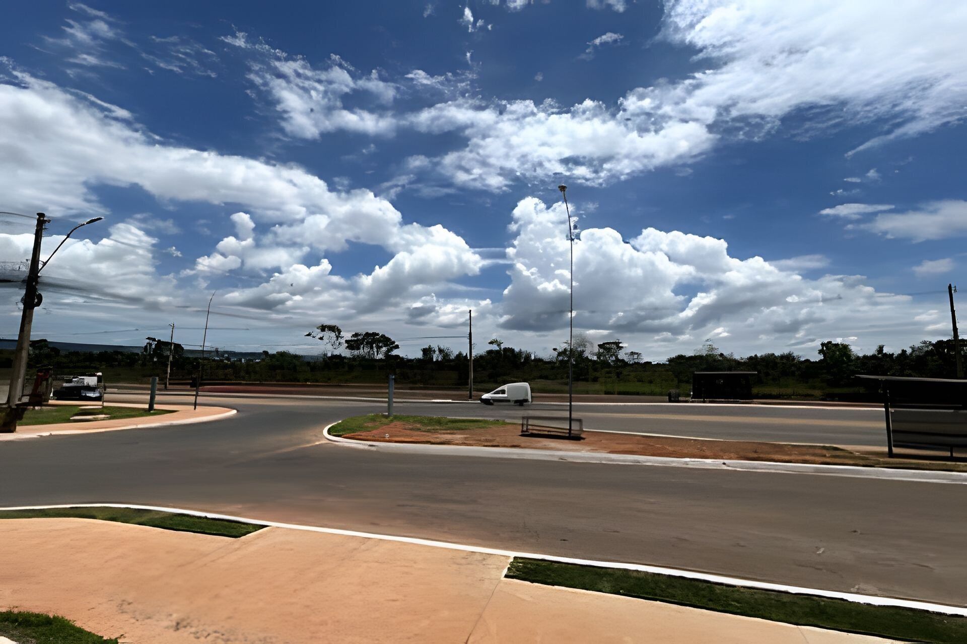 Una intersección con rotonda, farolas y una camioneta blanca.