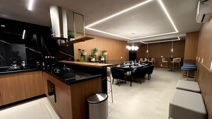 A modern kitchen with a central island, built-in appliances, and a dining area with a long table and chairs. - Noroeste - moderno e central (Brasília)