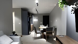 A modern living room with a sofa, a dining table with chairs, and a kitchen area in the background. - Noroeste - moderno e central (Brasília)