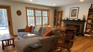 Ein Wohnzimmer mit einer Couch, Holzstühlen, einem Kamin und einem Bücherregal.
