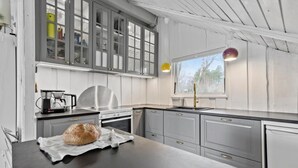 A modern kitchen with grey cabinets, a stainless steel stove, and a large window.