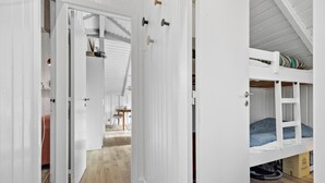 A room with a bunk bed, a wooden floor, and a door leading to another room.