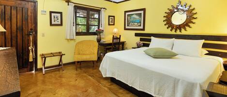 A bedroom with a bed, a chair, a desk, and a window.