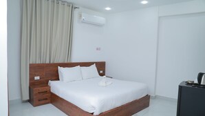 Una cama bien hecha con cabecera de madera, una mesita de noche y un pequeño aparador.