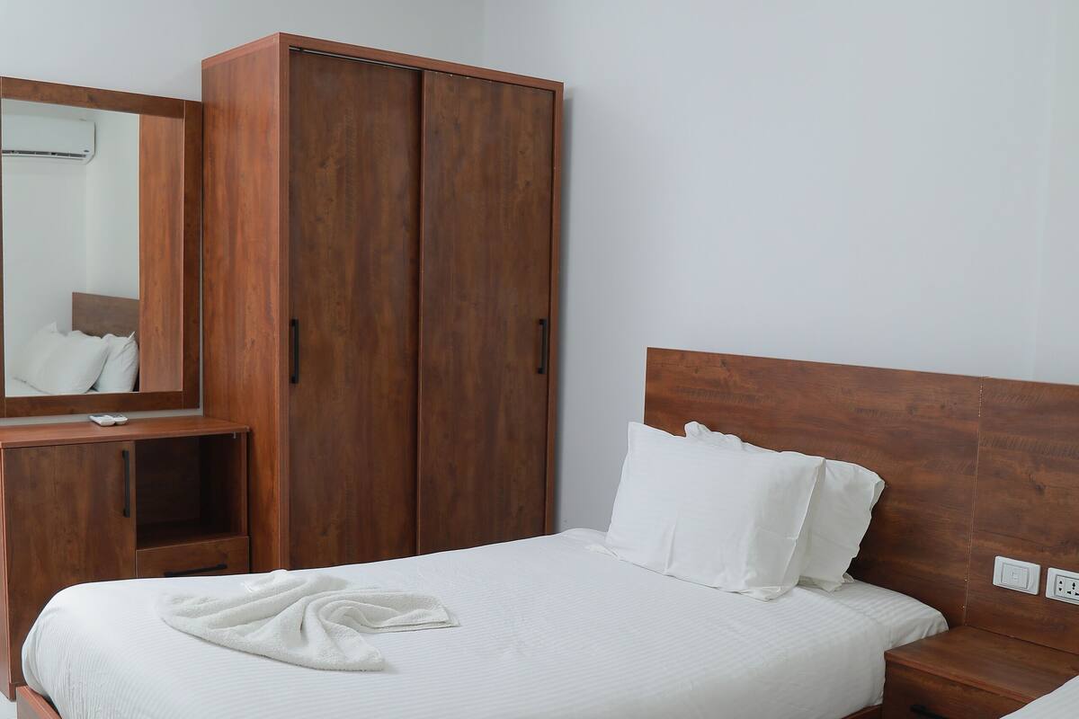 A modern bedroom with a wooden bed frame, white bedding, and a large wardrobe.