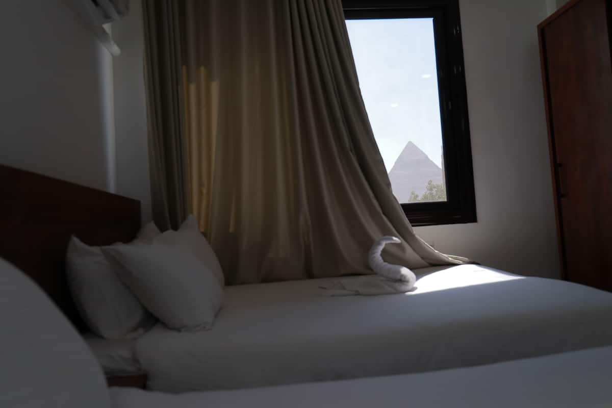 A bed with white bedding and a swan-shaped pillow.