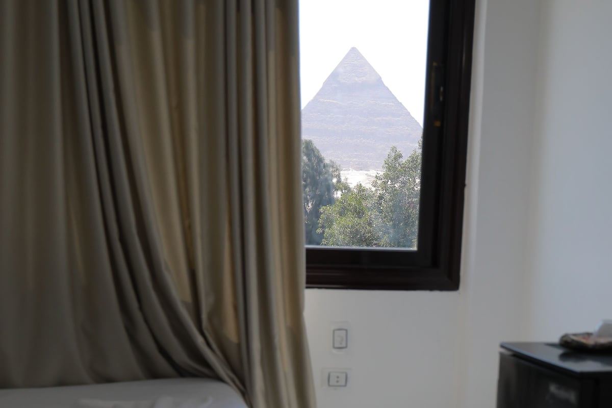 A bedroom with a bed, curtains, a window, and a television.
