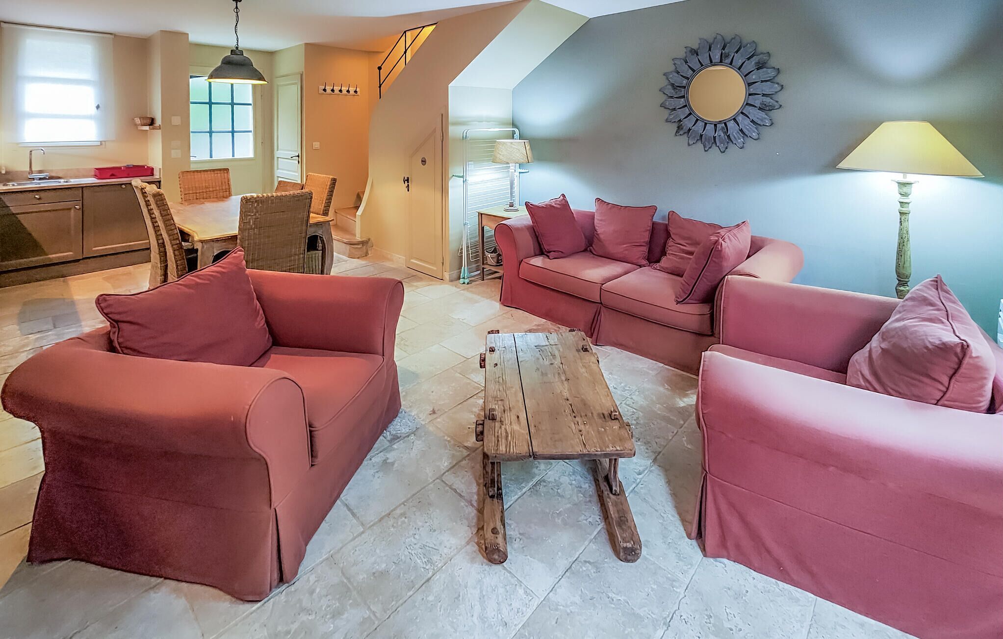A living room with a red sofa set, a wooden coffee table, and a sunburst wall decoration.