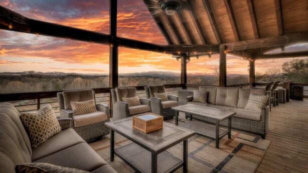 An outdoor seating area with wicker furniture and a view of the mountains at sunset.