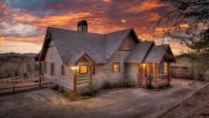 A log cabin with a steeply pitched roof, a chimney, and a garage.