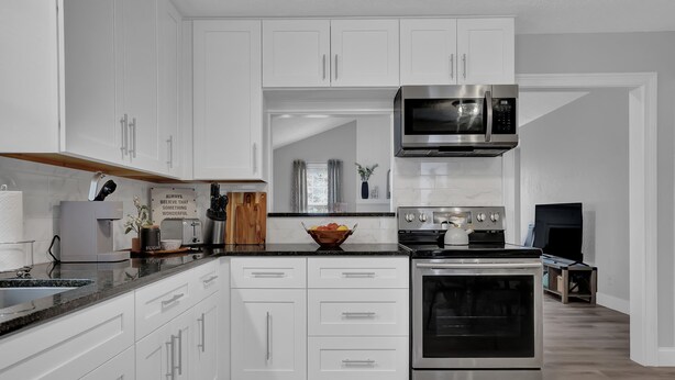 A modern kitchen with white cabinets, stainless steel appliances, and a wooden countertop. - Stylish Duplex! New Remodel! Minutes from Atlanta! (Norcross)