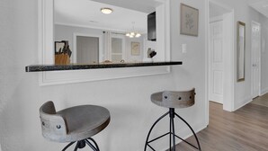 A kitchen with white walls, a black countertop, and two bar stools. - Stylish Duplex! New Remodel! Minutes from Atlanta! (Norcross)