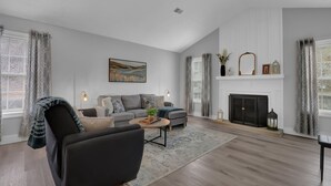 A modern living room with a sofa, armchair, fireplace, and artwork. - Stylish Duplex! New Remodel! Minutes from Atlanta! (Norcross)