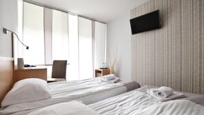 Une chambre d’hôtel avec deux lits, un bureau, une chaise, une télévision et une grande fenêtre.