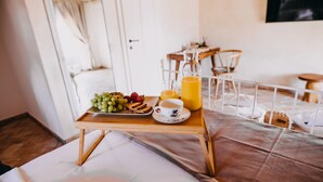 A breakfast tray with fruits, toast, and juice on a bed.