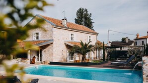 A stone house with a swimming pool, outdoor seating, and a well-maintained garden.