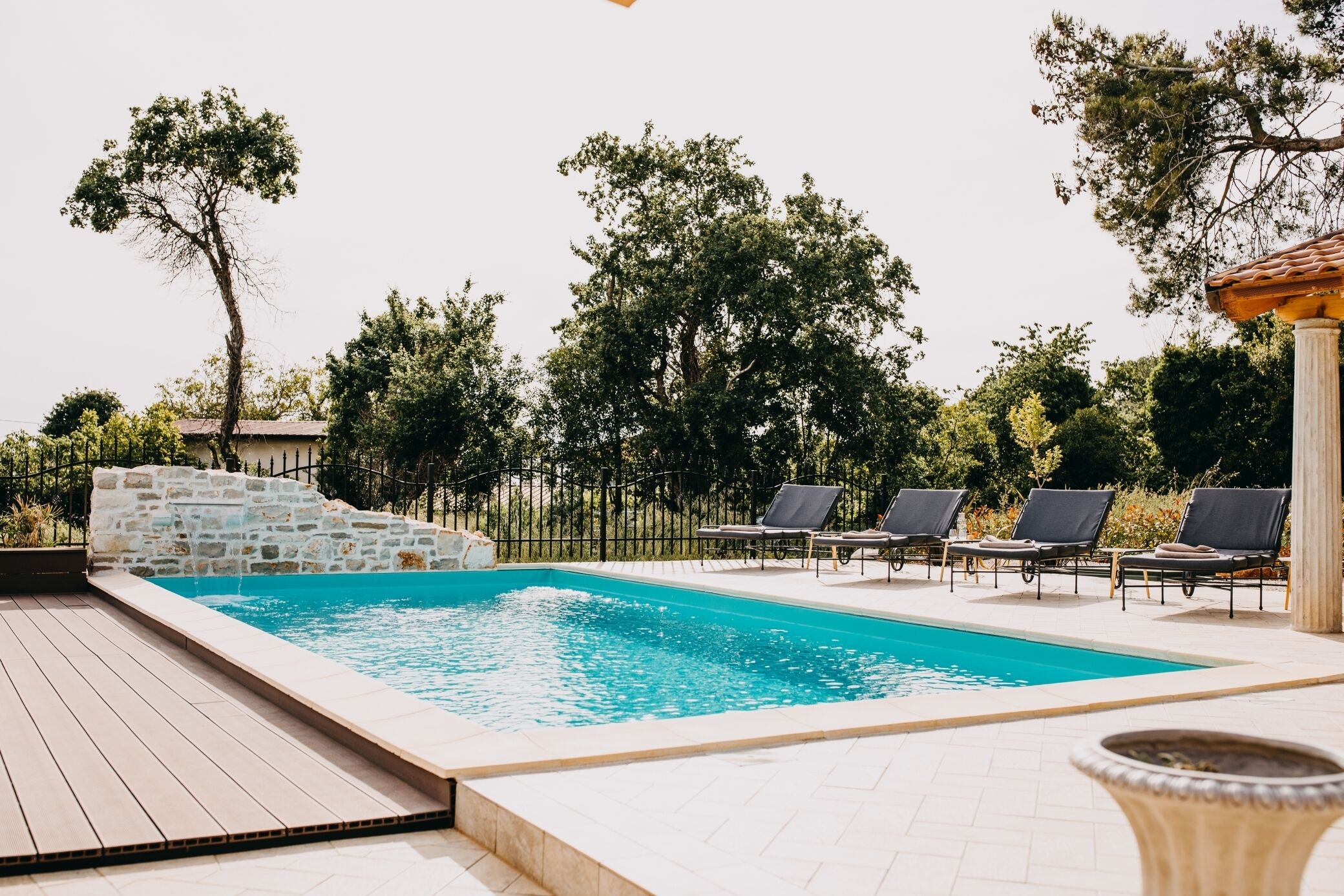 A swimming pool with lounge chairs and a stone wall.