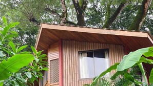 Ein hölzernes Haus mit rotem Dach, umgeben von üppigem Grün und einer Steintreppe, die zum Eingang führt.