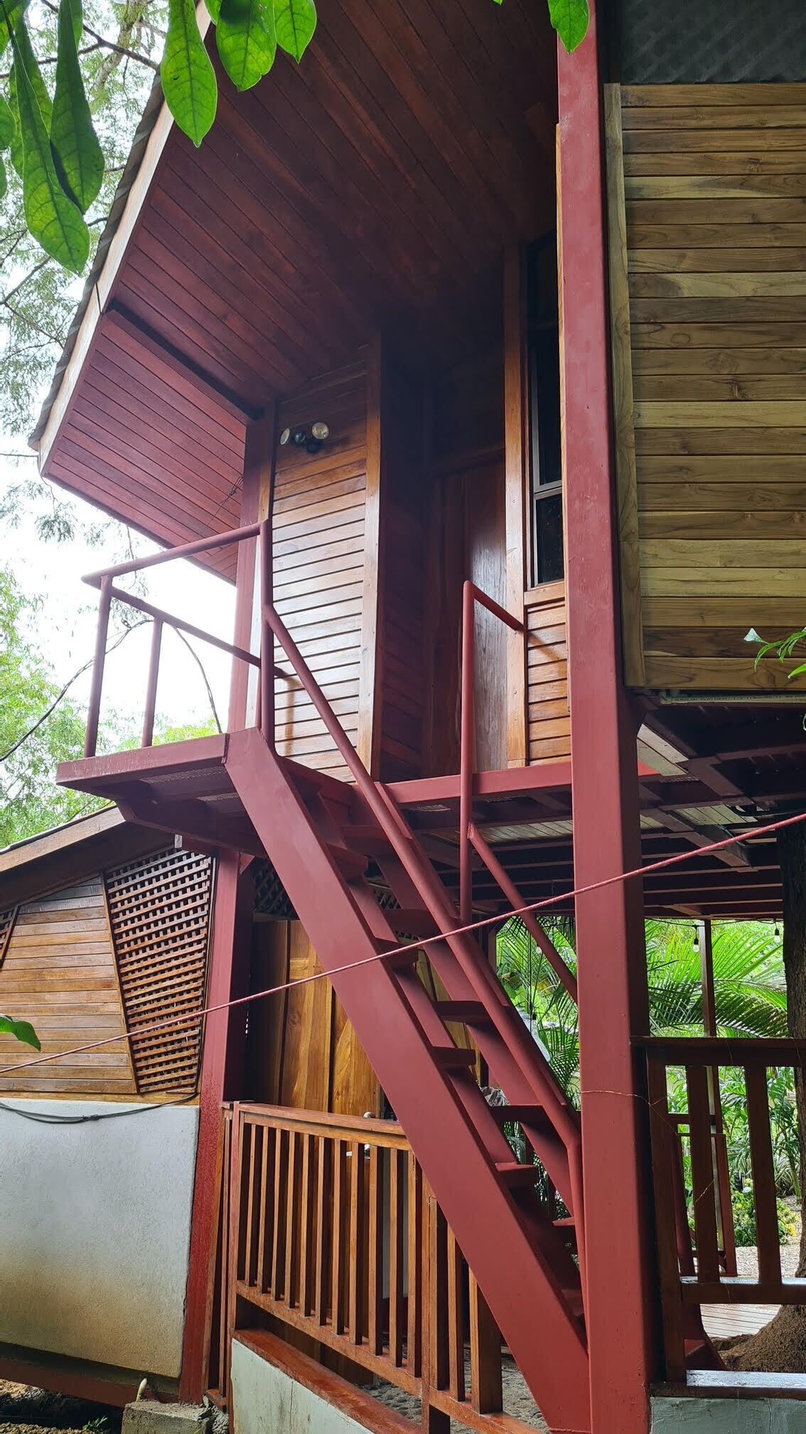 Eine Holzhütte mit einer roten Außentreppe, die zu einem Balkon führt.
