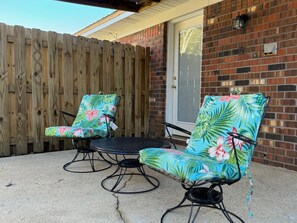 A patio with two chairs and a table, a wooden fence, and a brick wall. - Affordable Townhome in Gulf Breeze Florida is ready for guest. (Gulf Breeze)