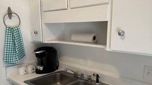 A kitchen with two stainless steel sinks, white cabinets, a coffee maker, and a tea kettle.