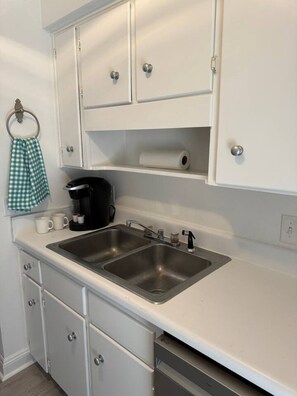 A kitchen with two stainless steel sinks, white cabinets, a coffee maker, and a tea kettle. - Affordable Townhome in Gulf Breeze Florida is ready for guest. (Gulf Breeze)