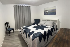 A bedroom with a bed, a chair, a painting, and a view of the outdoors. - Affordable Townhome in Gulf Breeze Florida is ready for guest. (Gulf Breeze)