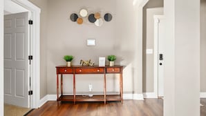 Un bureau en bois, agrémenté de deux plantes en pot, d’un élément décoratif fixé au mur et d’une porte dotée d’une poignée noire.