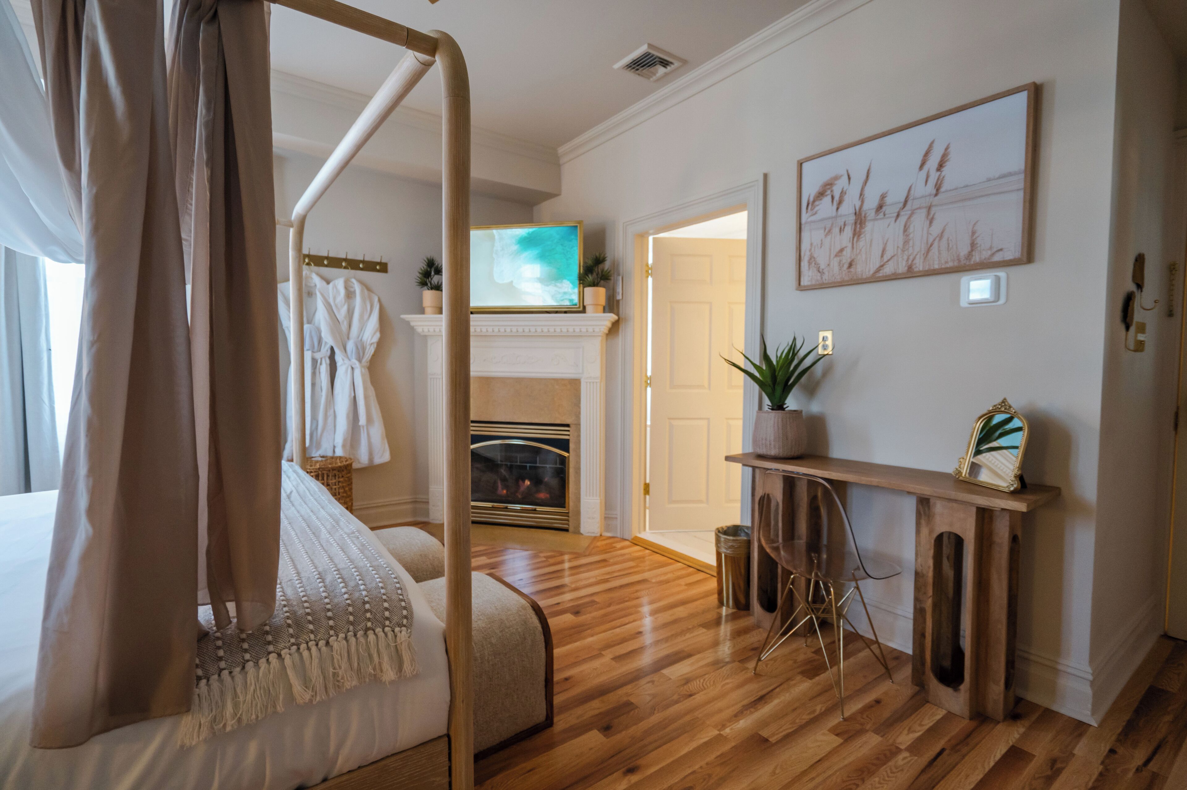 Une chambre à coucher avec un lit à baldaquin, une cheminée, un téléviseur et un tableau au mur.