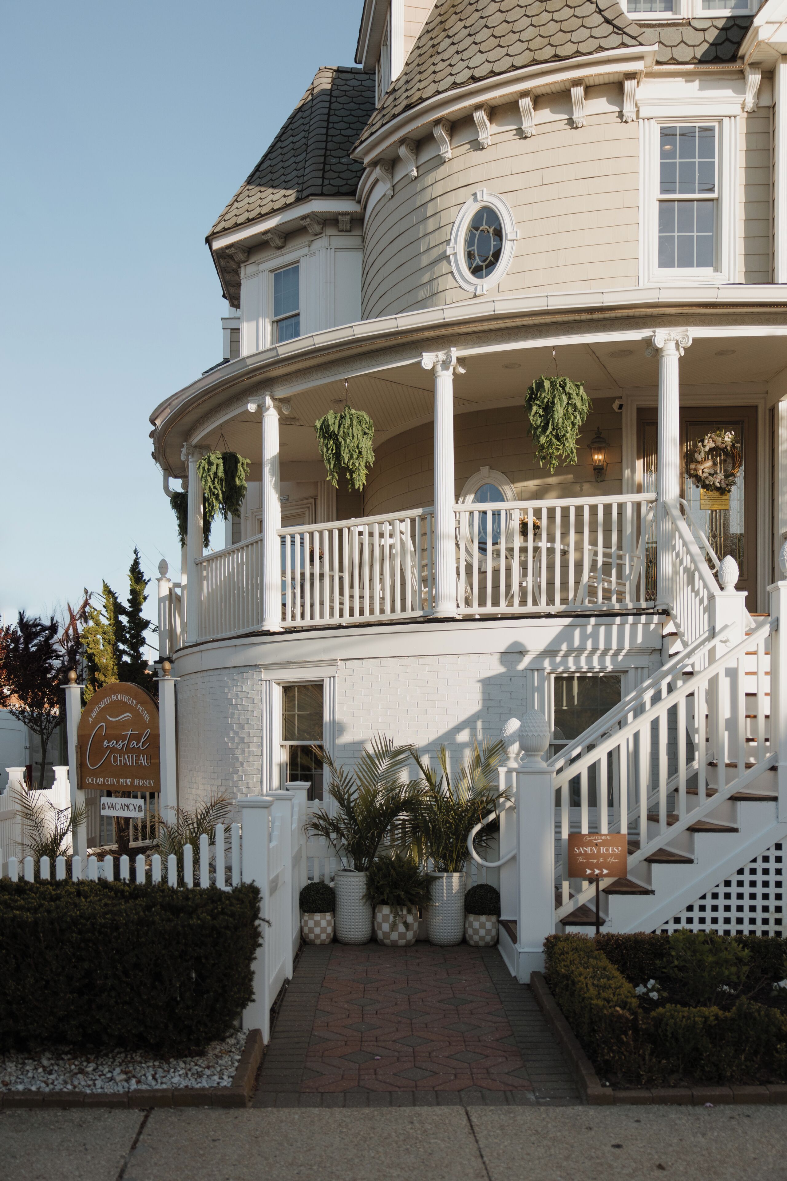 A two-story building with a curved facade, a balcony with white railings, and a staircase leading to the entrance.