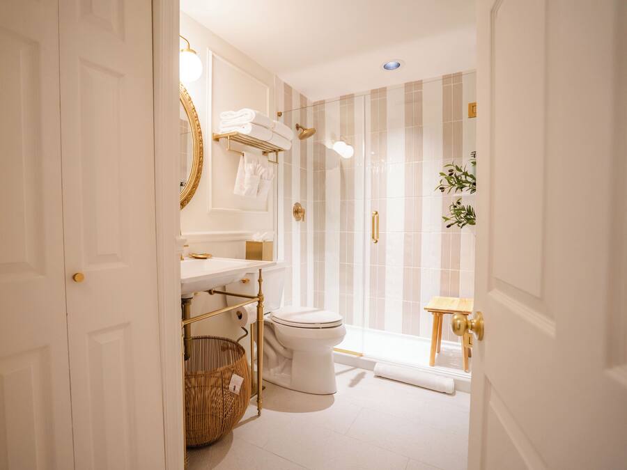 A bathroom with a white toilet, a sink with a gold faucet, and a shower with a glass door.