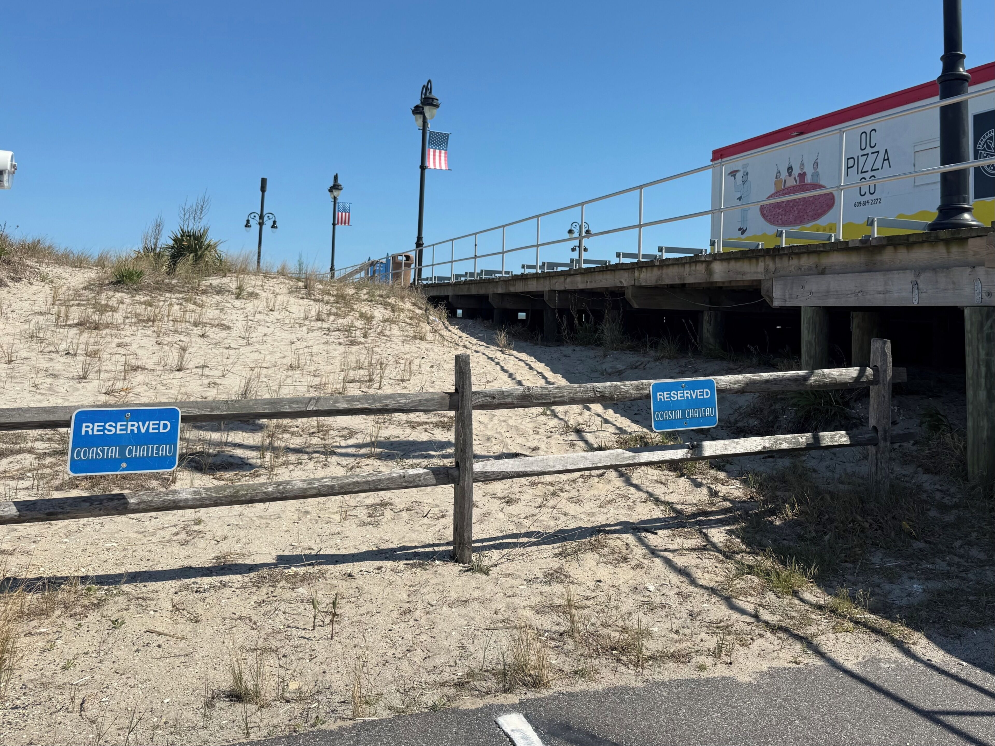 Een kustgebied met een bord 'RESERVED COASTAL CHATEAU', een strand en een pizzeria onder een brug.