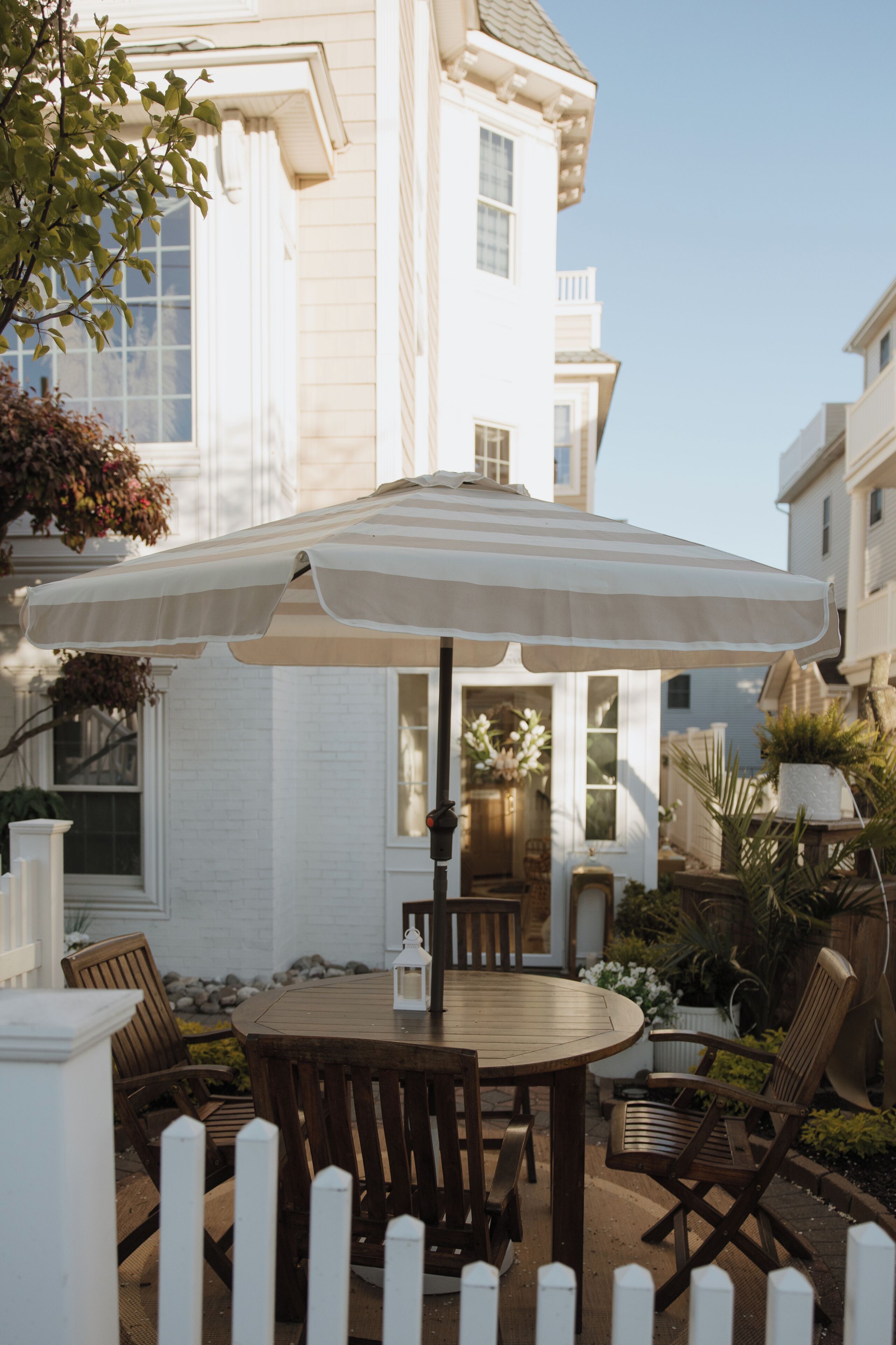A patio with a round wooden table, chairs, and a large umbrella.