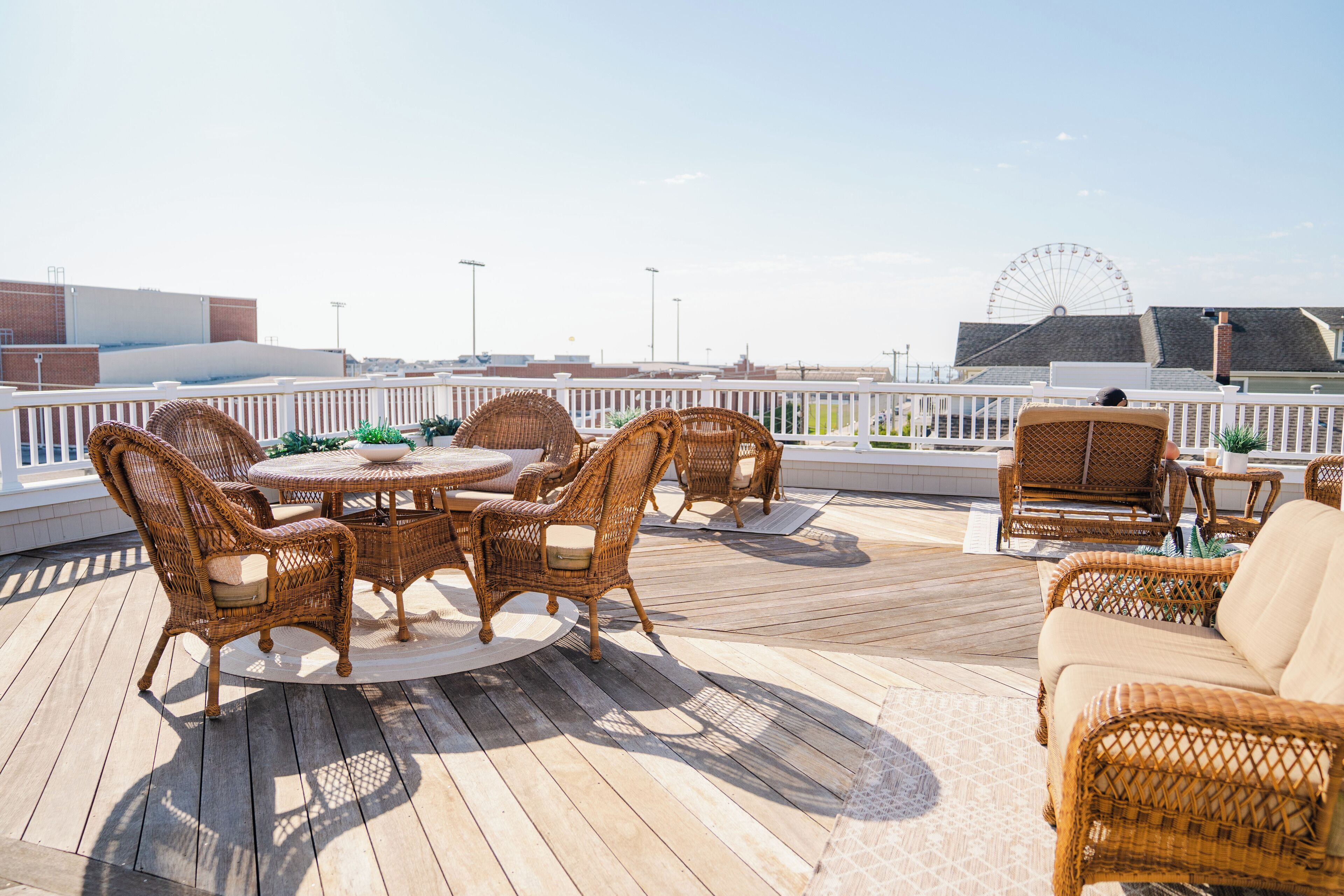 Eine Terrasse mit Korbmöbeln, einem runden Tisch und Blick auf ein Riesenrad.