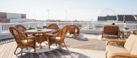 Eine Terrasse mit Korbmöbeln, einem runden Tisch und Blick auf ein Riesenrad.