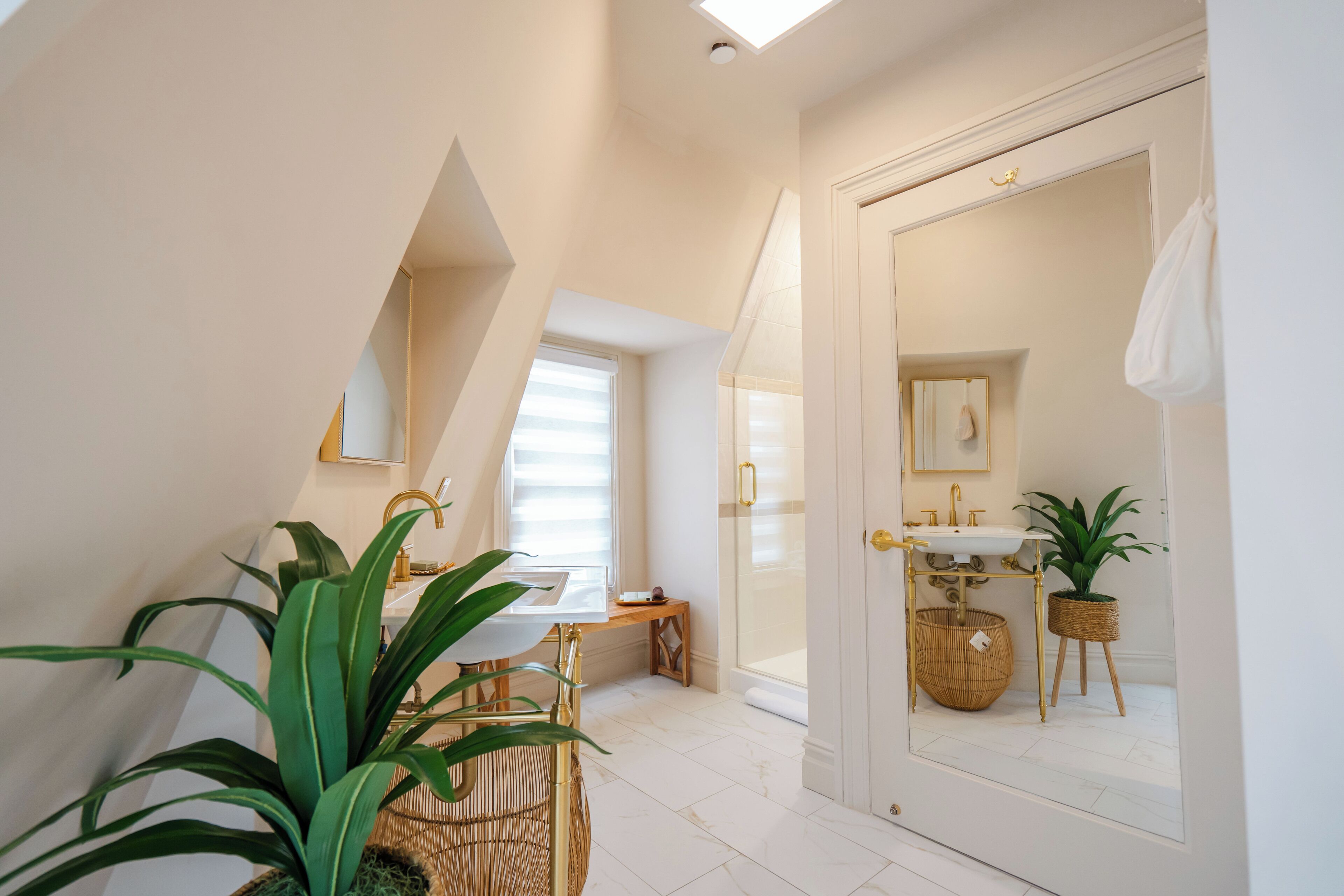 A modern bathroom with a large mirror, a sink, and a window.